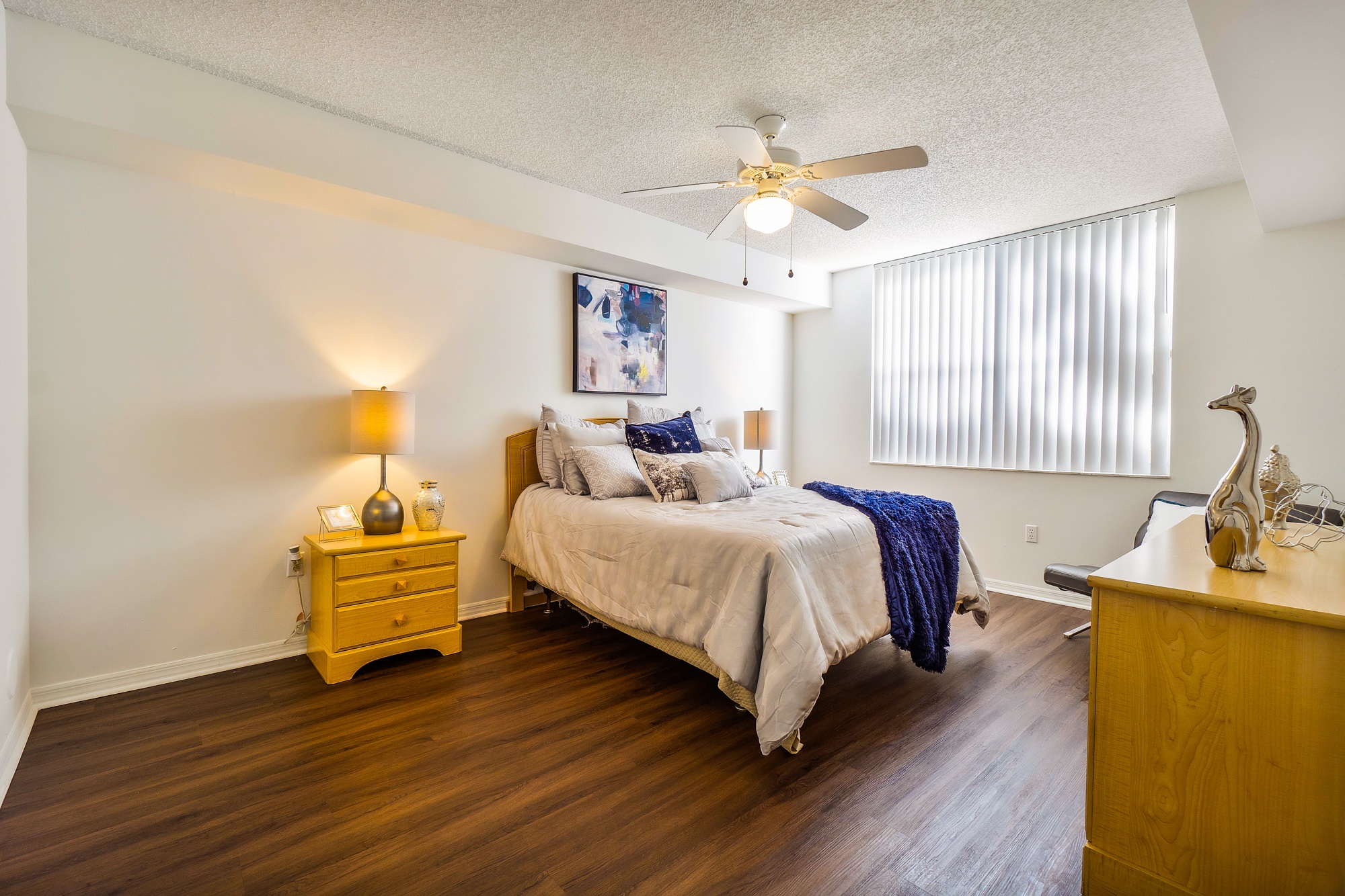 A bedroom with a bed, nightstand, and a ceiling fan.
